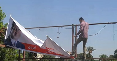 مواطنون يحاولون الاستيلاء على لافتات المرشحين بعد إزالتها بالعجوزة